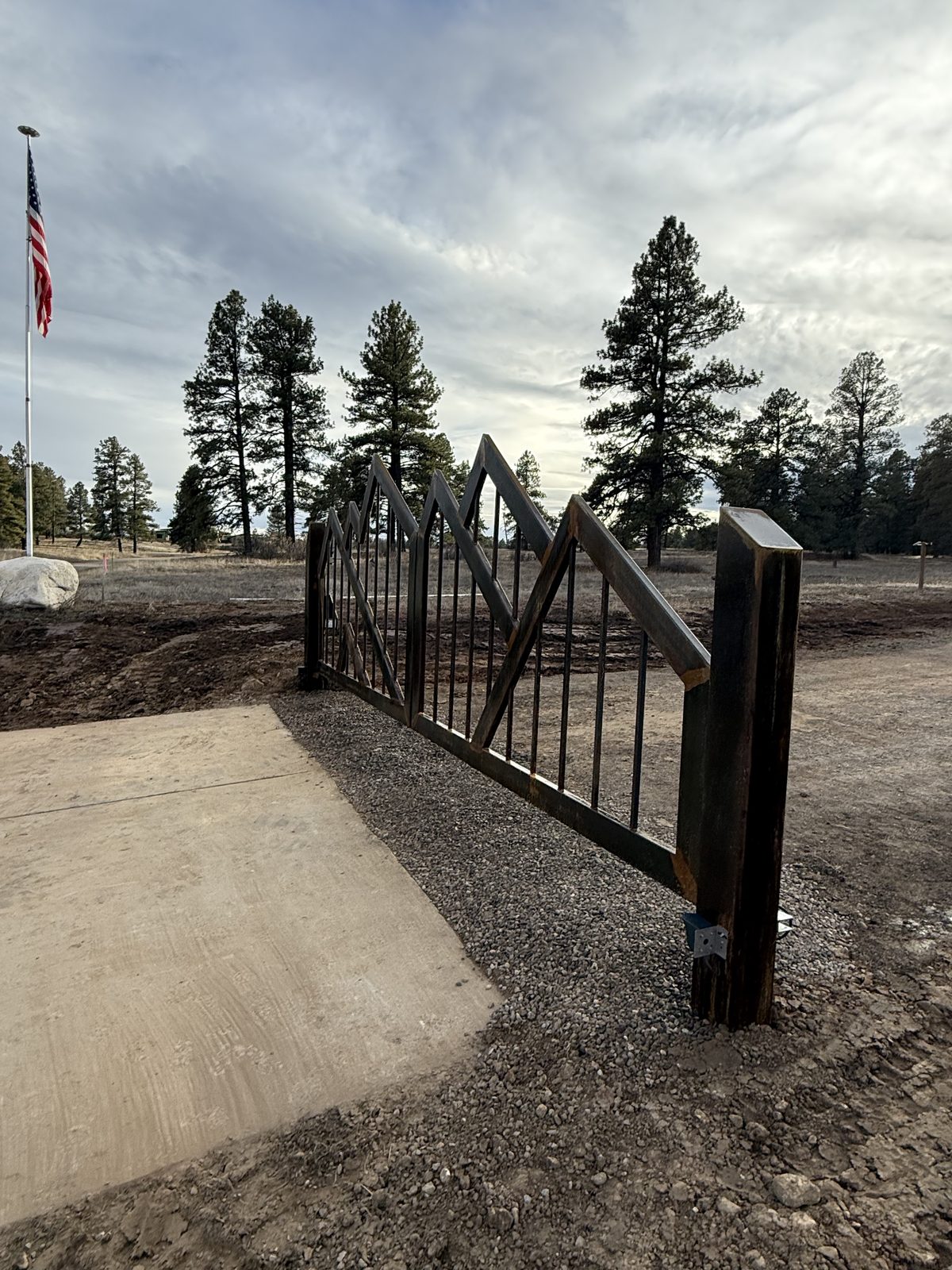 Installed black steel gate with American flag and concrete apron